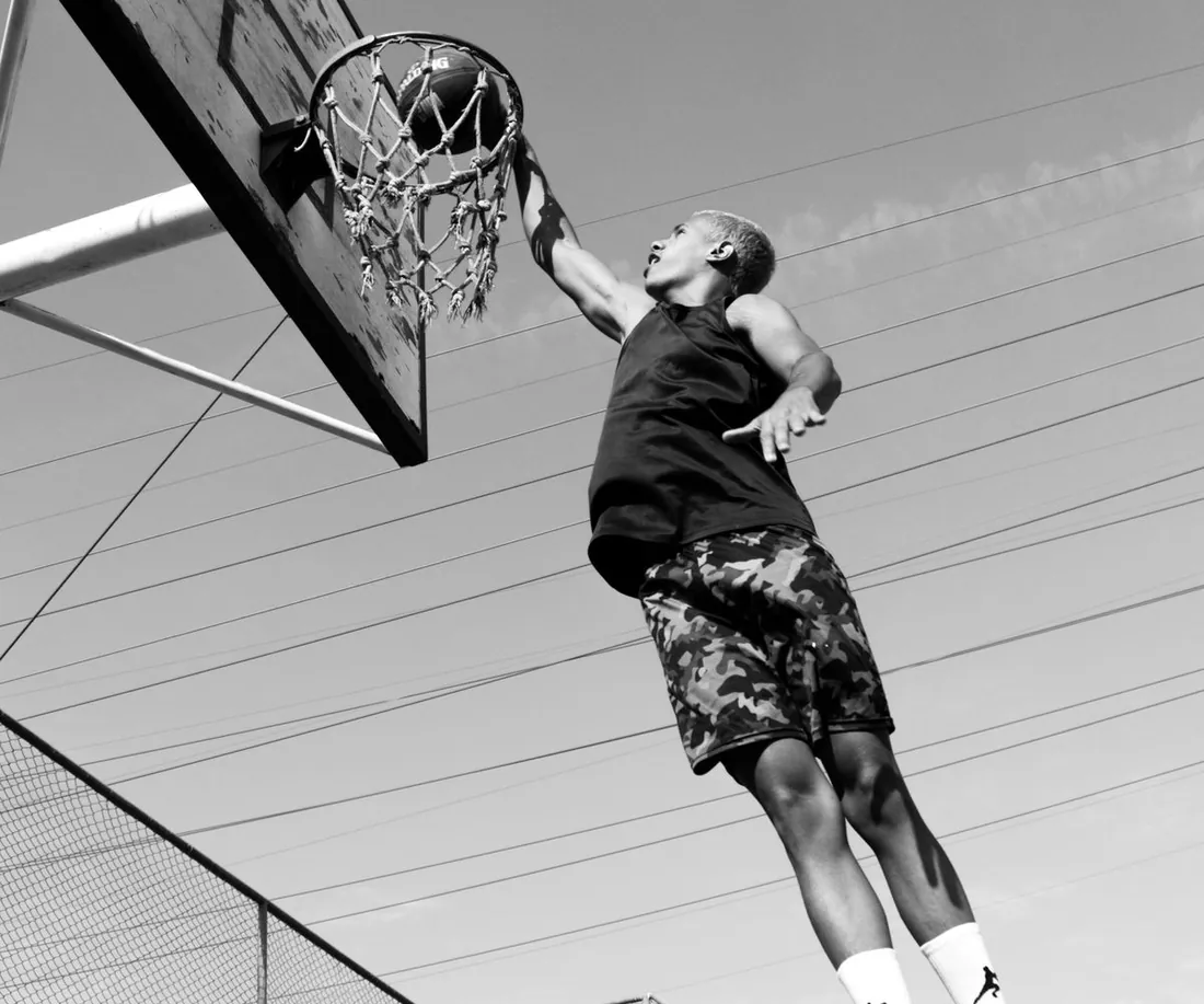 A player rises to the rim on an outdoor basketball court