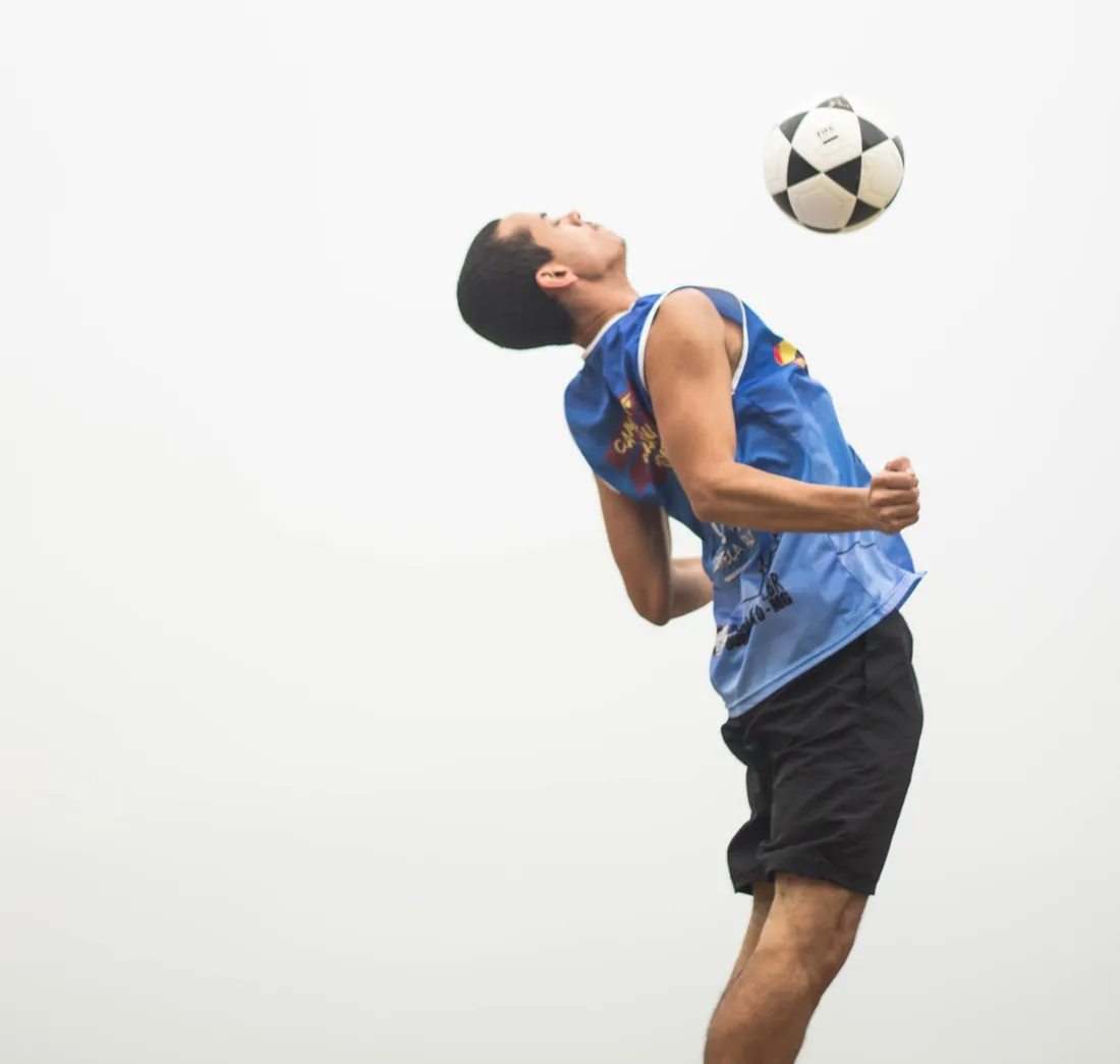 A player leans back to chest a soccer ball on a beach