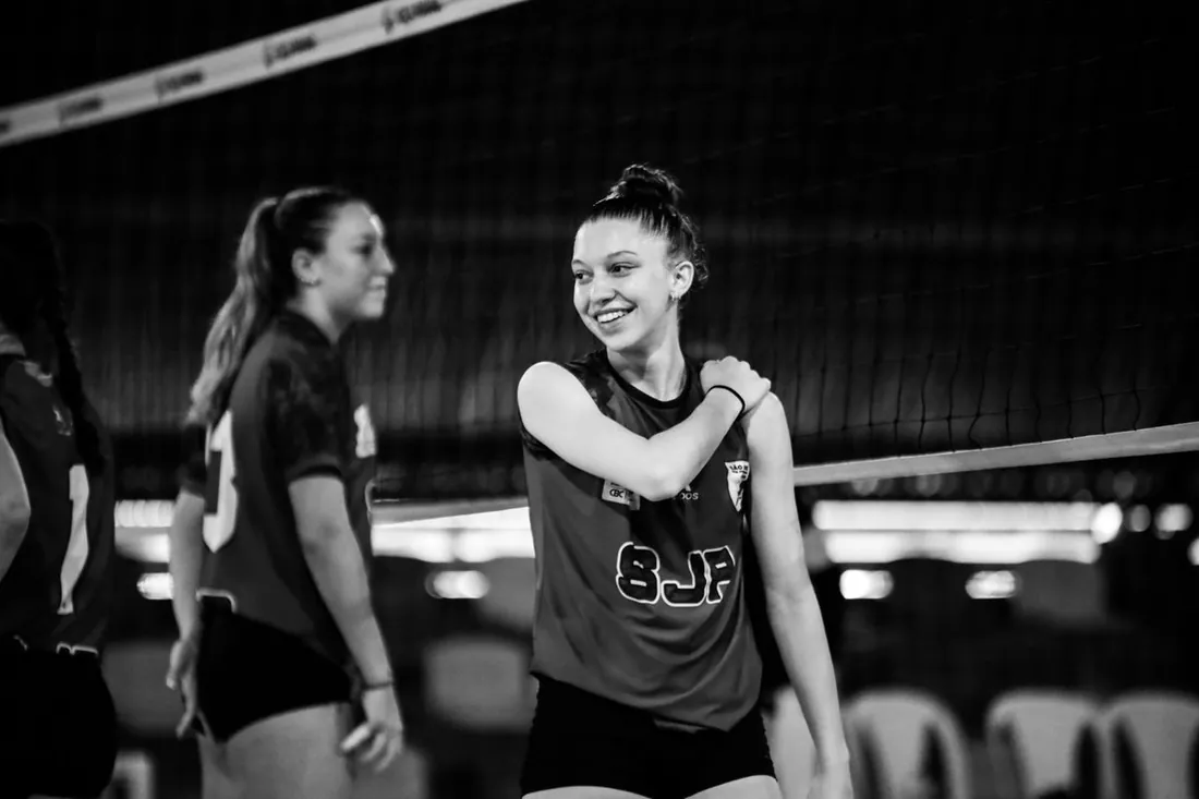 Two volleyball players laugh at the net on an indoor court