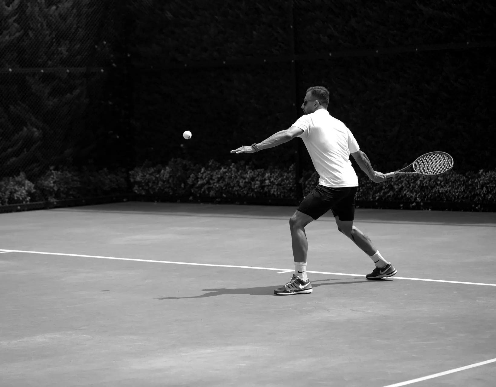 A tennis player reaches for a forehand on an outdoor court